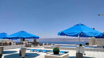 Una piscina al aire libre, sombrillas, sillones reclinables de piscina