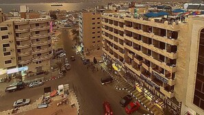 A multi-story parking garage with several levels of parking, surrounded by buildings. - Mass Paradise Hotel (Aqaba)
