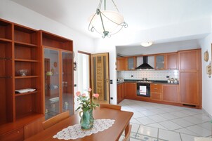 Una cocina con armarios de madera, una estufa y un comedor con mesa y jarra.