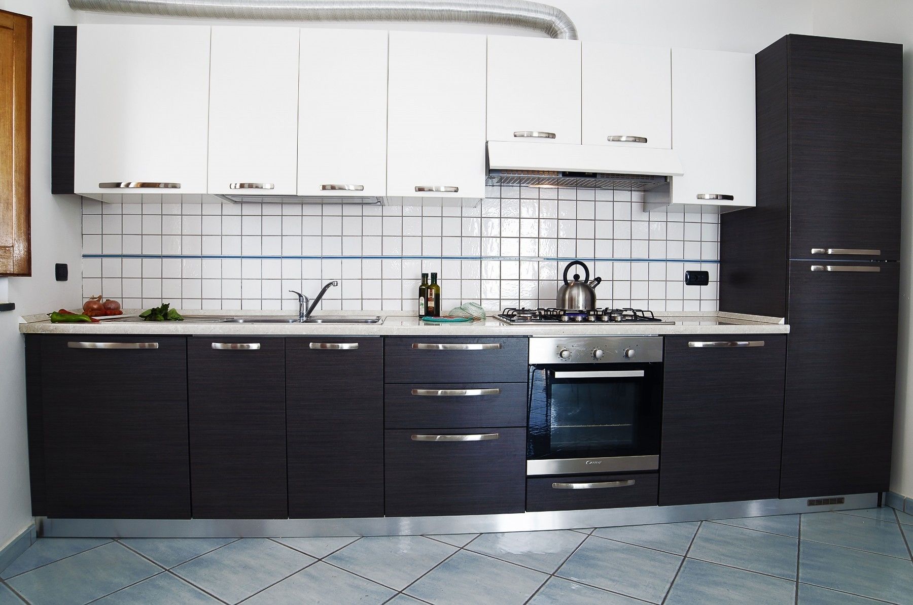 A modern kitchen with dark cabinetry, a stainless steel stove, and a tiled backsplash.