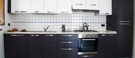 A modern kitchen with dark cabinetry, a stainless steel stove, and a tiled backsplash.
