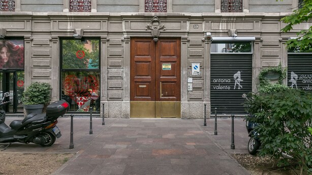 A building facade with a central entrance, two closed shutters on either side, and a number '29' above the door. - notaMi -  Borsieri 29 (Milan)