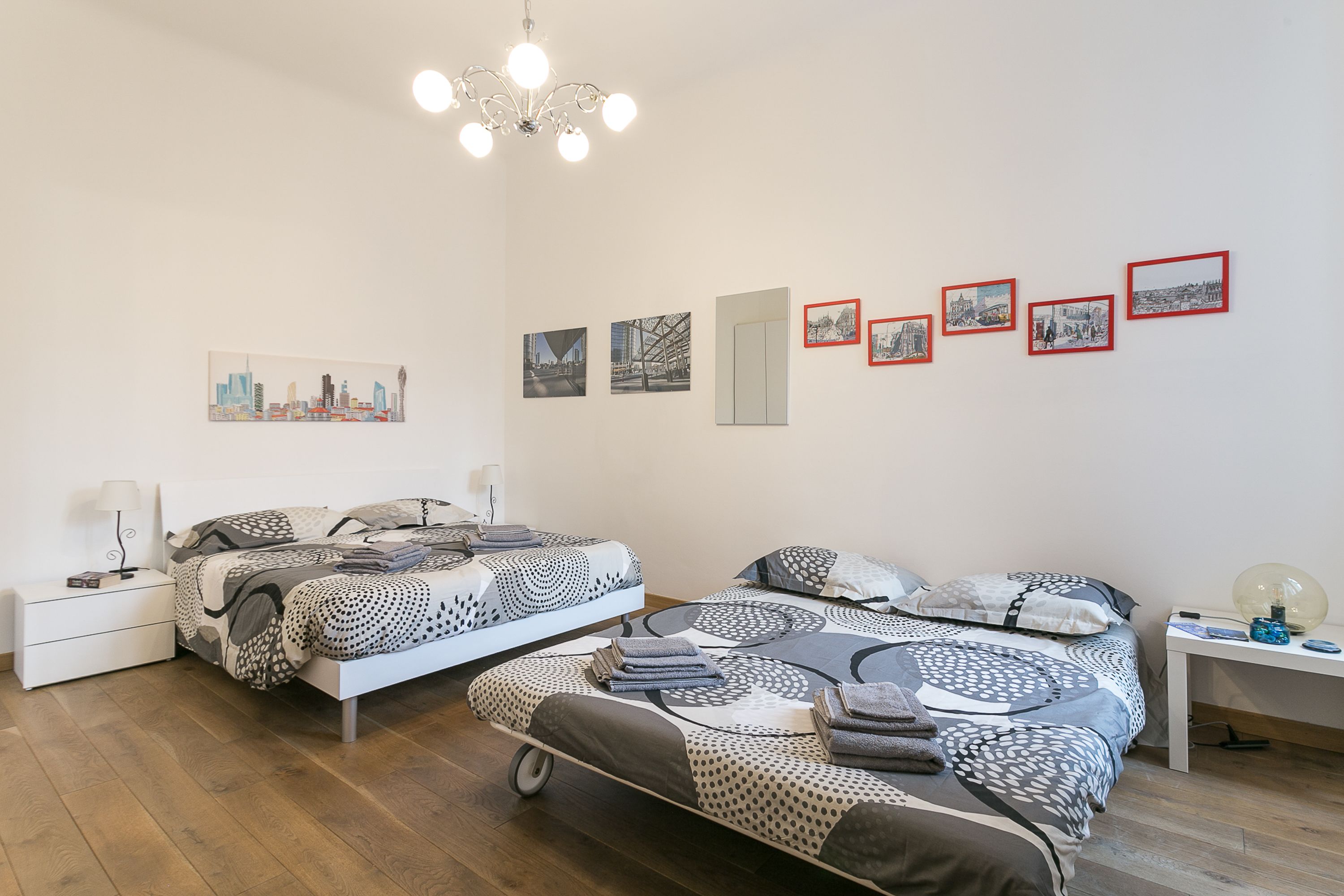 Une chambre moderne avec deux lits, une table de chevet, un bureau et un lustre.