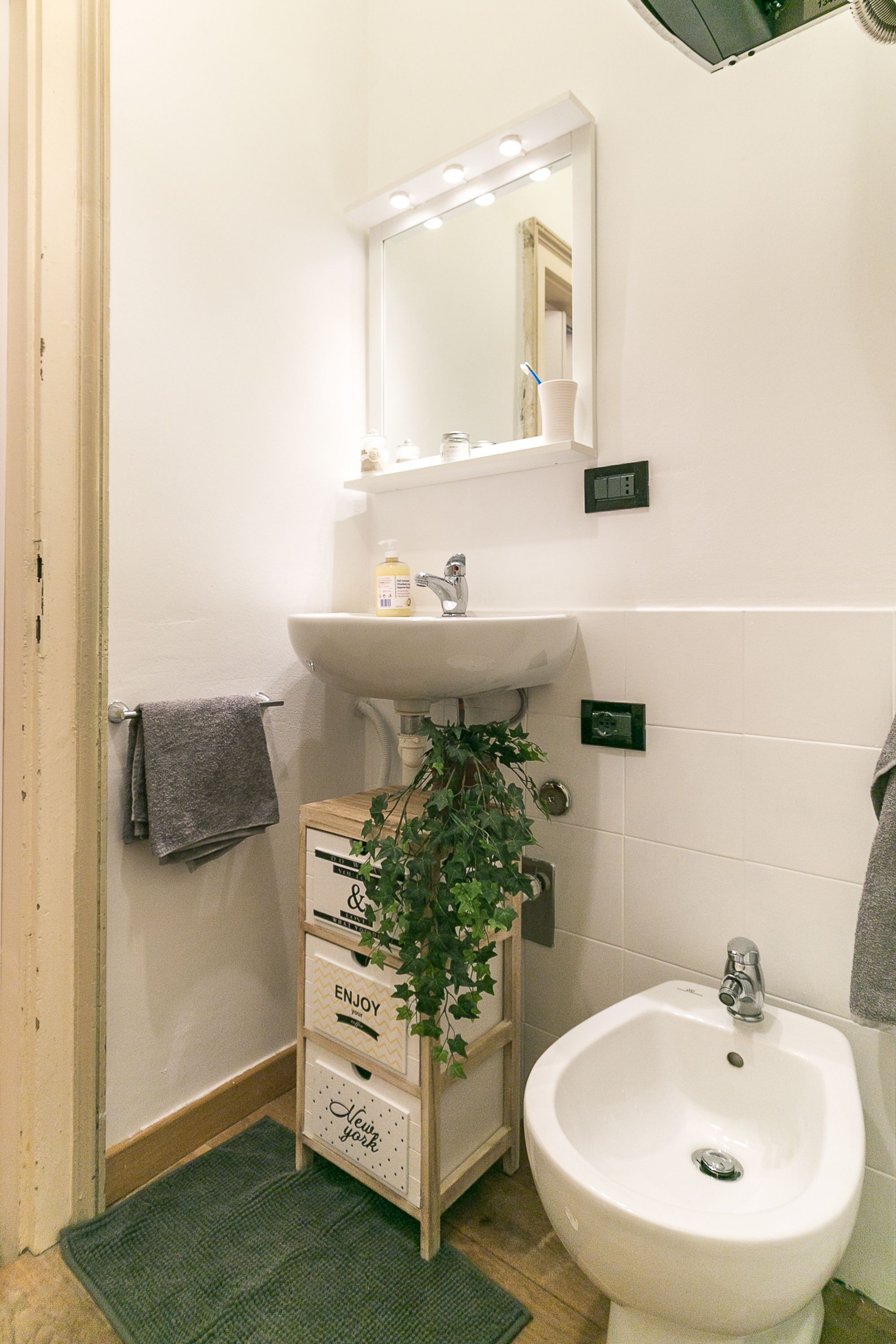 A bathroom with a white sink, mirror, and a wooden cabinet with drawers.