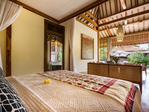 Een slaapkamer met een groot bed, een houten plafond, een schilderij en uitzicht op buiten.