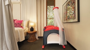 A hotel room with a bed, a bedside table with a lamp, a window with blinds, and a wall-mounted artwork. - Villa Desa Roro Estate by Villa Finder (Canggu)