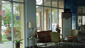A reception area with a sofa, chairs, a lamp, and a potted plant.