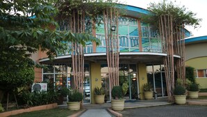 A hotel with a curved entrance, large potted plants, and a glass door.
