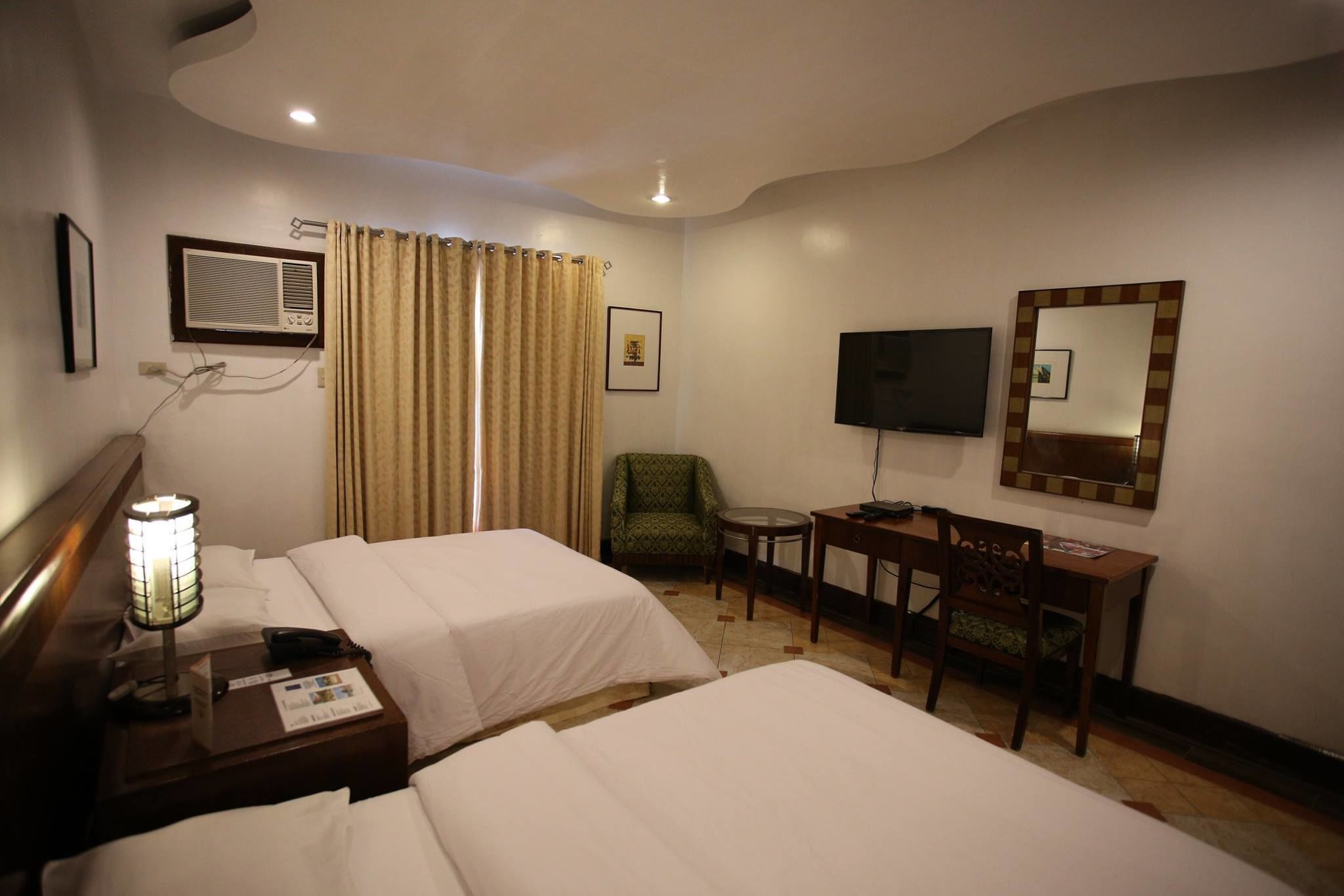 Habitación de hotel con dos camas, un escritorio, una silla, un televisor y un espejo.