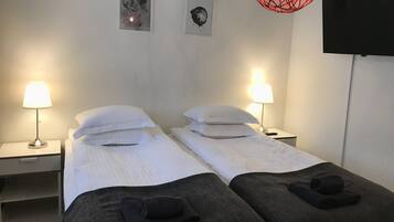Hotellihuoneessa on kaksi erillistä sänkyä, joissa kummassakin on tyyny ja taitettu pyyhe. Huoneessa on myös kaksi yöpöytää, joissa on lamput, seinälle asennettu televisio sekä kaksi kehystettyä kuvaa seinällä.