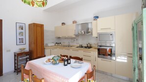 Une cuisine moderne avec un coin repas, équipée d’une cuisinière, d’un four et de divers appareils de cuisine.