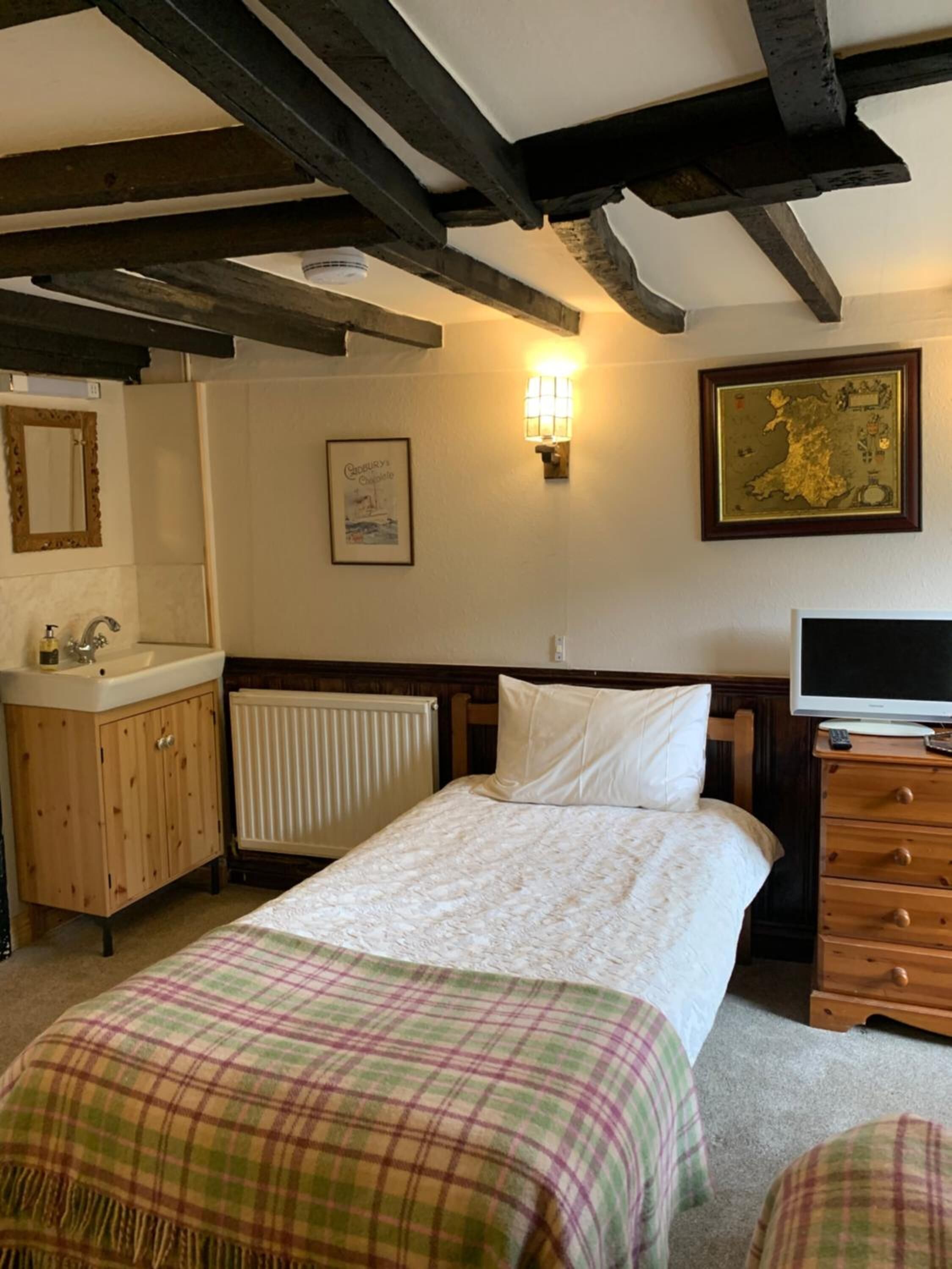 Un dormitorio con cama, cómoda de madera, televisor y radiador.