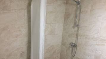 A shower with a curtain, a handheld showerhead, and a wall-mounted faucet.