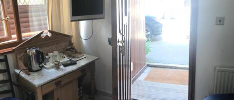 A compact kitchen with a built-in stove, a small sink, and a microwave. There is a television mounted on the wall above the counter.