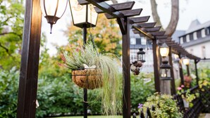 En pergola med hængende plantekasser og lanterner i en have.