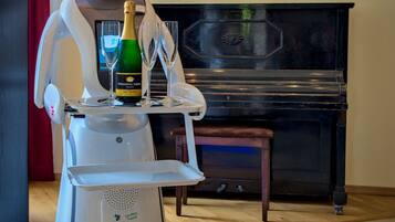 Een robot met een champagnefles en glazen op een dienblad, een piano en een lijst met een schilderij aan de muur.