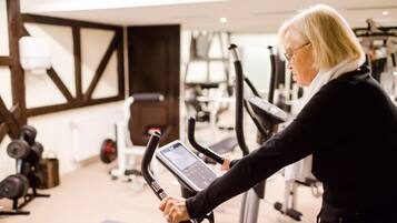 Een sportschool met trainingsapparatuur, waaronder een hometrainer en gewichten.