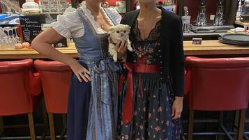 Dos personas con vestimenta tradicional en un bar, con un letrero que dice "Oktoberfest".