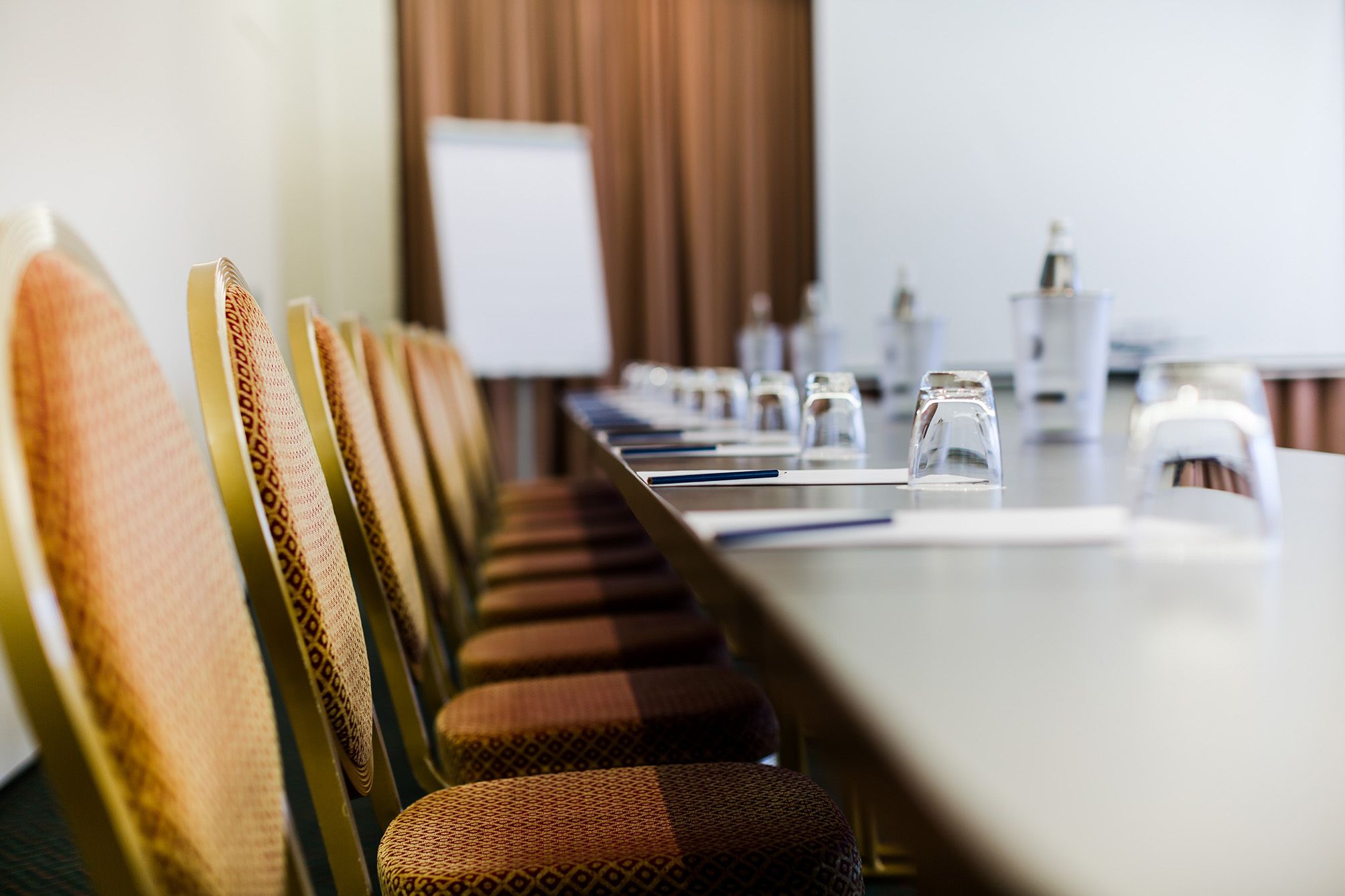 A conference room with a long table, chairs, and water glasses.
