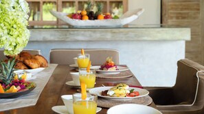 A breakfast setting with croissants, fruit, and beverages on a wooden table. - Mannao Estate by Villa Finder (Kerobokan)