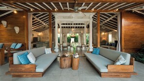 A spacious lounge area with two sofas, a coffee table, and a ceiling fan. - Mannao Estate by Villa Finder (Kerobokan)