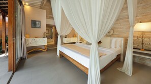 A bedroom with a canopy bed, wooden flooring, a white bedside table with a lamp, and a decorative mirror. - Mannao Estate by Villa Finder (Kerobokan)
