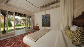 A bedroom with a large bed, a view of the outdoors, and a painting on the wall. - Mannao Estate by Villa Finder (Kerobokan)