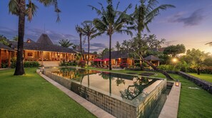 A resort with a swimming pool, palm trees, and traditional architecture. - Mannao Estate by Villa Finder (Kerobokan)