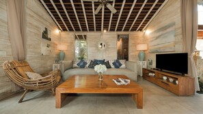 A living room with a wooden ceiling, a sofa, a television, and a coffee table. - Mannao Estate by Villa Finder (Kerobokan)