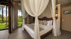 A four-poster canopy bed with a view of a lush garden. - Mannao Estate by Villa Finder (Kerobokan)