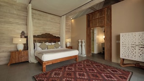 A bedroom with a wooden bed, a patterned rug, a nightstand with a lamp, and a wardrobe. - Mannao Estate by Villa Finder (Kerobokan)