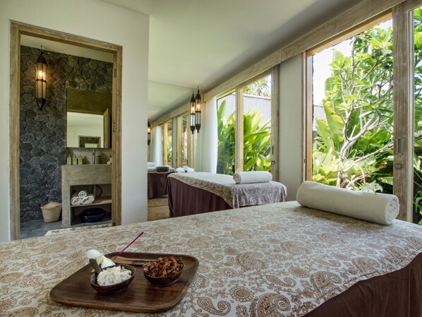 A spa room with a massage table, towels, and a tray with food items. - Mannao Estate by Villa Finder (Kerobokan)