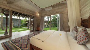 A bedroom with a large bed, a patterned rug, and a view of a garden. - Mannao Estate by Villa Finder (Kerobokan)