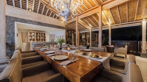 A spacious dining area with a long wooden table set for a meal, surrounded by comfortable seating.