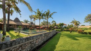 A resort with a swimming pool, palm trees, and thatched-roof buildings. - Mannao Estate by Villa Finder (Kerobokan)
