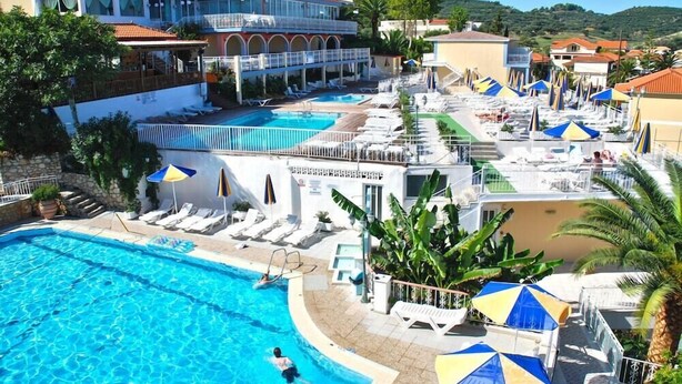 A hotel with multiple swimming pools, sun loungers, and umbrellas.
