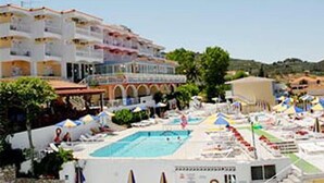 A hotel with a swimming pool, multiple balconies, and a view of the surrounding landscape.