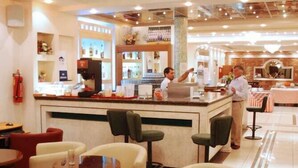 A hotel lobby with a bar area, seating arrangements, and a chandelier.