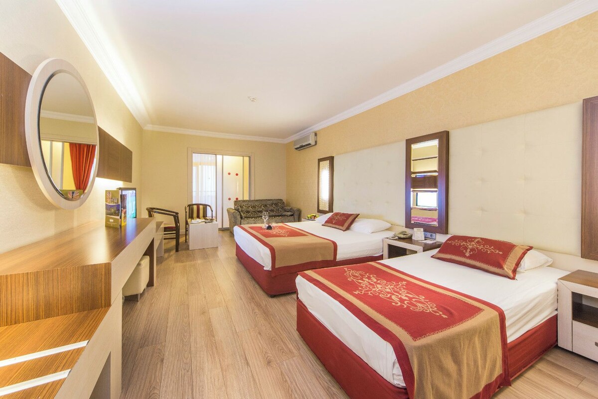Une chambre d’hôtel avec deux lits, un bureau, une chaise, un miroir et une fenêtre.