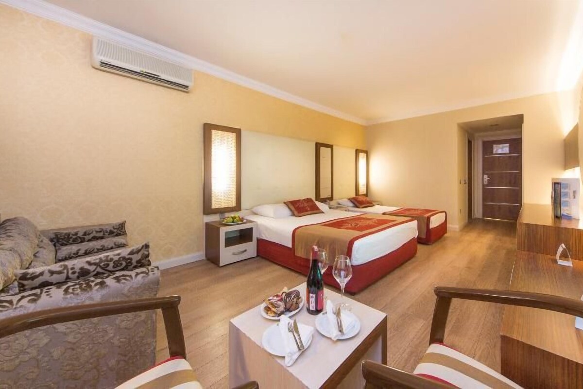 Une chambre d’hôtel comprenant un lit, des tables de chevet, une télévision, un bureau avec des chaises et un canapé.