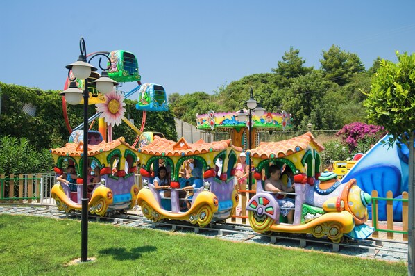A colorful train ride with passengers, surrounded by greenery and a clear sky. - Beach Club Doganay (Alanya)
