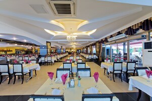 Un restaurante espacioso con varias mesas y sillas, un candelabro y unidades de aire acondicionado.