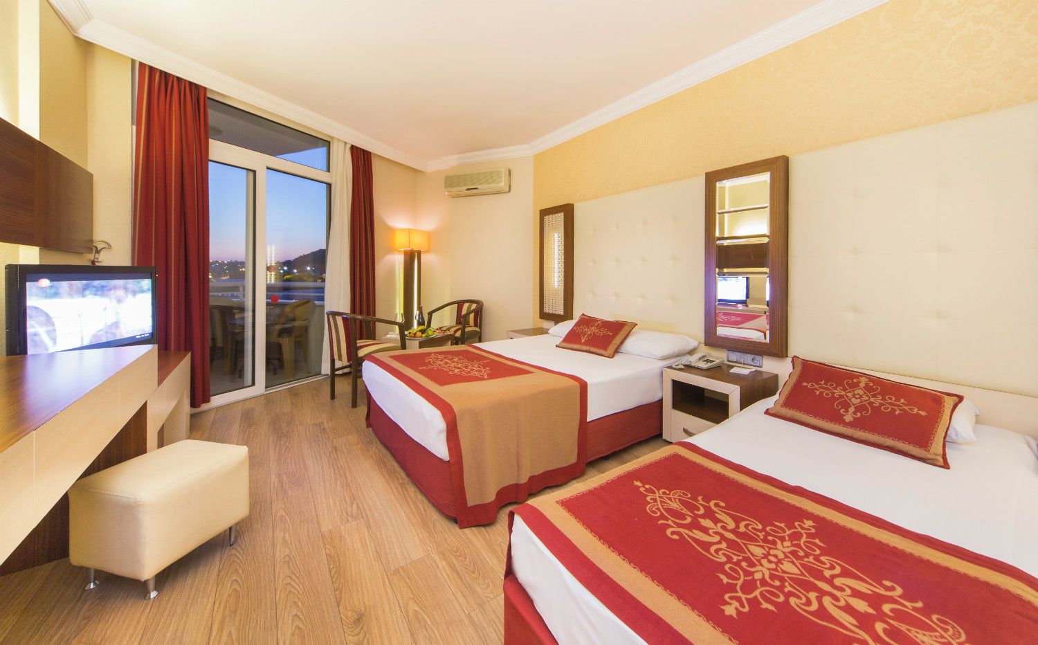 A hotel room with two beds, a TV, a desk, and a chair.