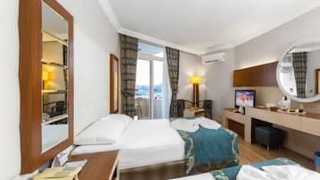 A hotel room with two beds, a desk, a chair, a TV, and a bathroom with a mirror.