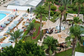 Un complexe hôtelier doté d’une piscine, de chaises longues et de palmiers.