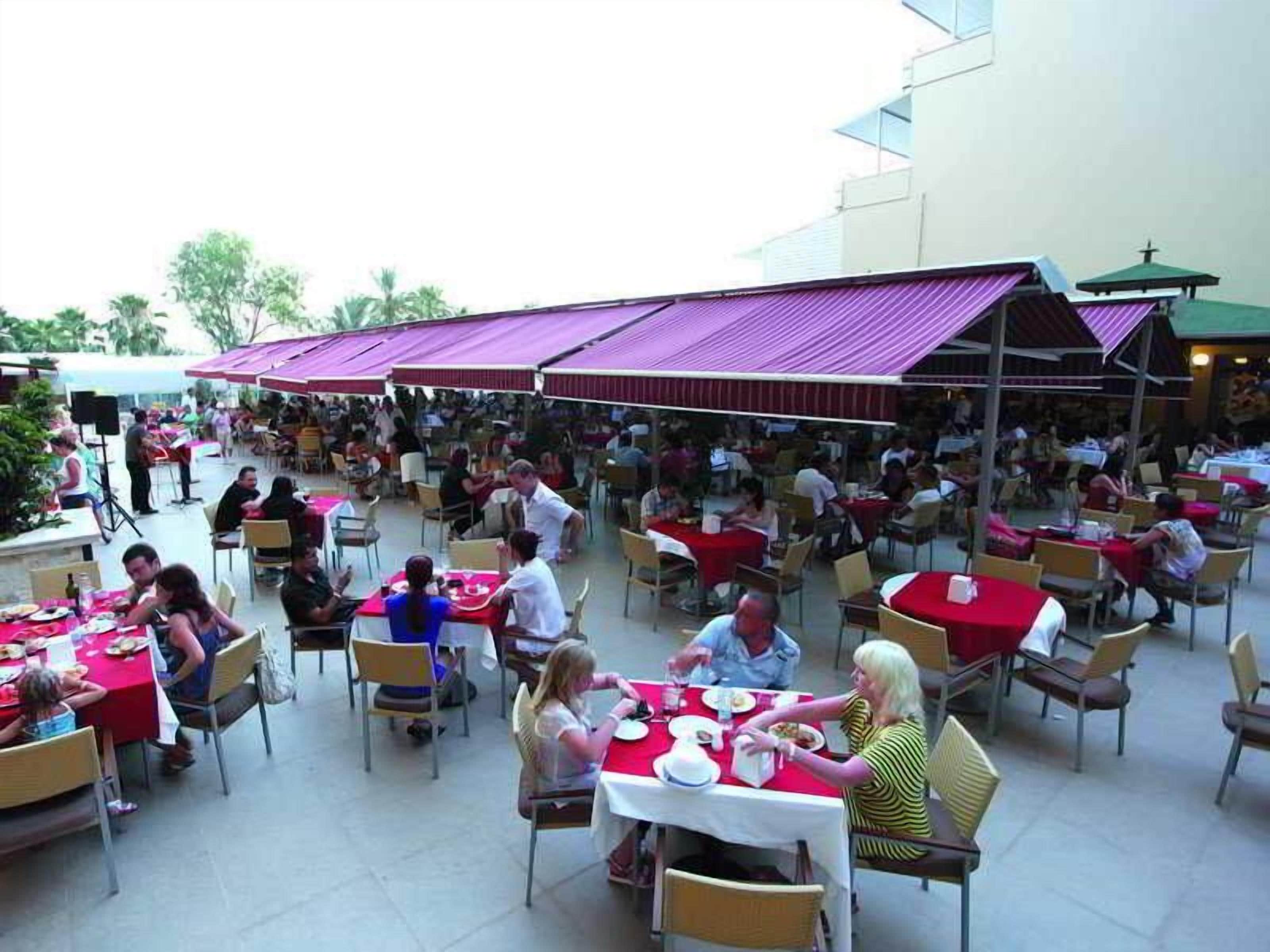 An outdoor dining area with multiple tables and chairs, covered by umbrellas.