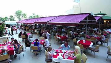 An outdoor dining area with multiple tables and chairs, covered by umbrellas.