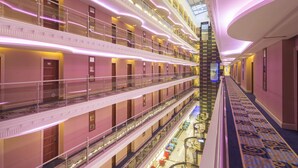 Interior de un hotel de varios niveles con balcones, un atrio central y una alfombra estampada.