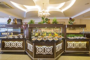 Un espace buffet doté de plusieurs points de service, de vases décoratifs et d’un lustre.