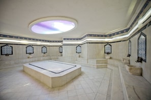 A spacious room with a large central area, a skylight, and decorative wall tiles. - Beach Club Doganay (Alanya)